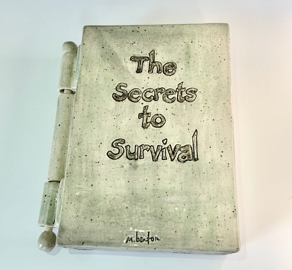Ceramic book by Marla Benton titled "The Secrets to Survival"