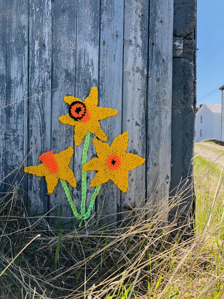 photo of knitted daffodils against an outdoor wooden structure